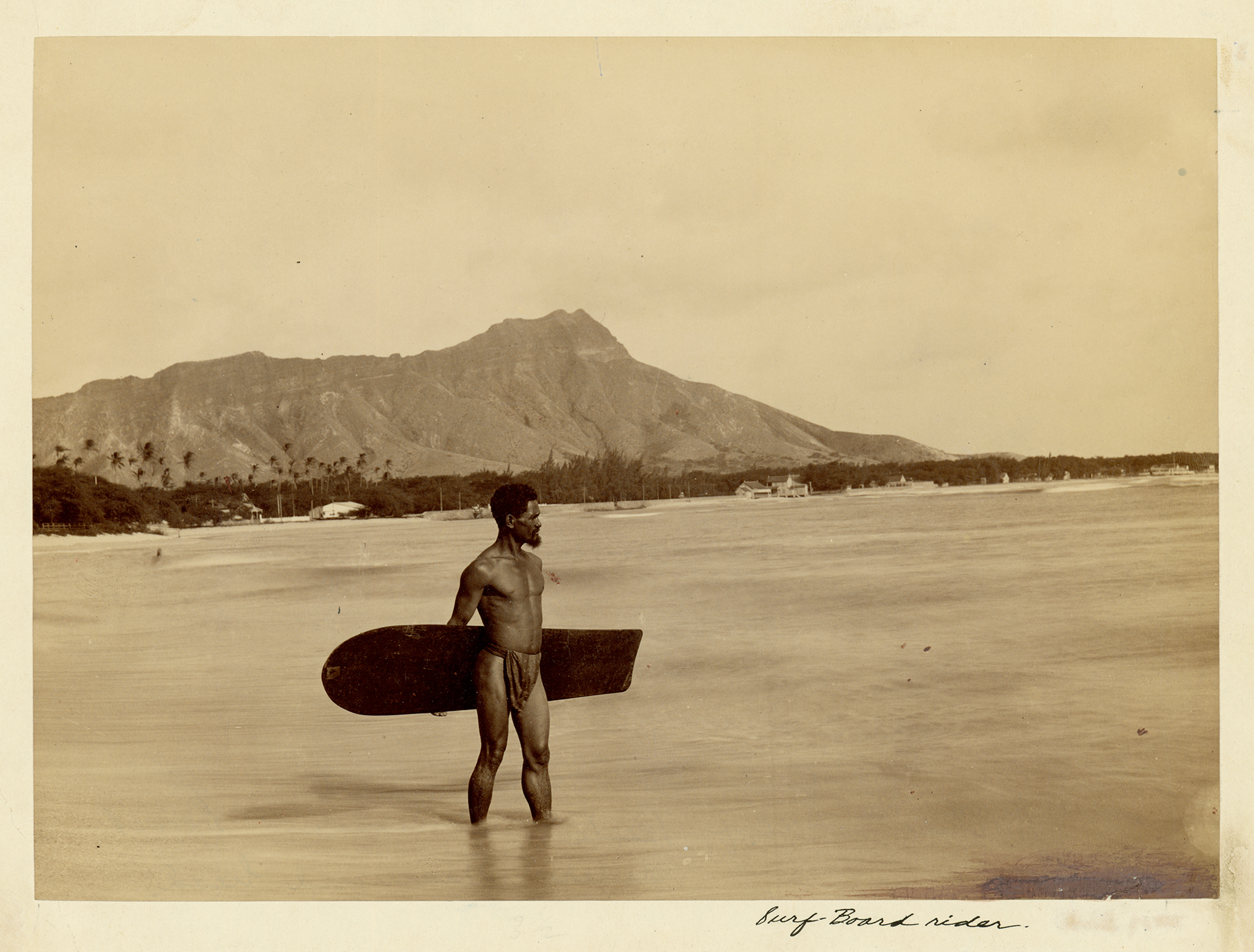 [Hawaiian man with surfboard] Diamond Head in background; Waikīkī, ca. 1890. Photographer unknown.